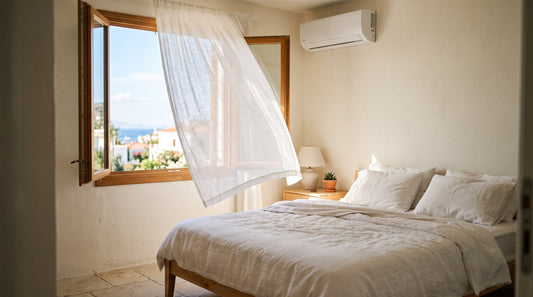 Dormitorio mediterráneo con aire acondicionado en la pared y cortina de lino al viento, para el artículo sobre a qué temperatura poner el aire acondicionado