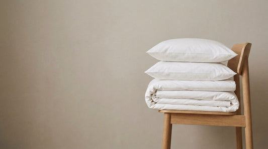 Ropa de cama blanca doblada sobre una silla de roble: cada cuánto cambiar sábanas y toallas